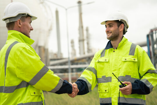 Engineer worker hand shaking to colleagues team for success work at construction site of petroleumchemical industry or refinery oil plant factory