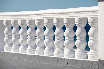 A white railing sits on a beach, overlooking the ocean