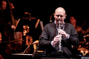 Jazz Clarinet. A clarinettist in the spotlight performing on stage with drums and bass visible in...