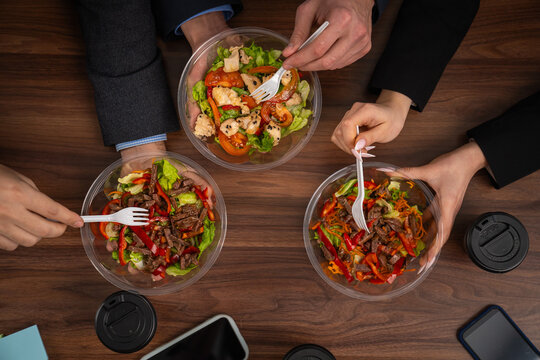 Three colleagues enjoy fresh salads during office lunch break