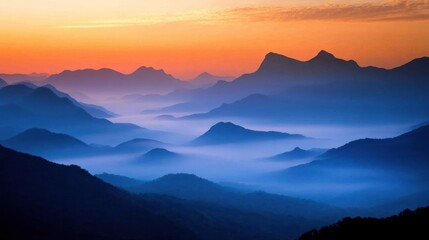 Fototapeta premium Misty mountain range at sunrise. Layers of peaks and valleys shrouded in colorful morning mist