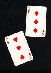 A pair of playing cards of the same value isolated on a black background.