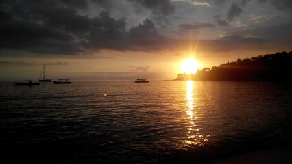 A sunset over the water with boats visible in Senggigi Beach Indonesia