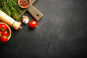 Kitchen utensils, wooden cutting board and food ingredients on black.