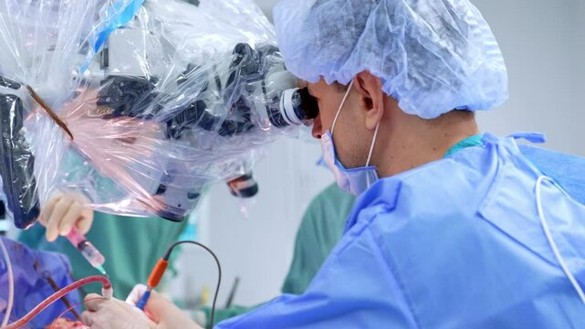 Confident male Caucasian surgeon looks at microscope. Doctor carefully uses electric tool devices.