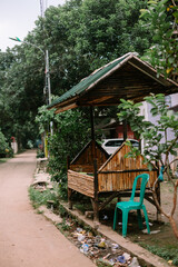 Rustic bamboo structure with green roof and a plastic chair by the roadside