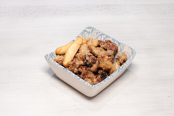 A bowl of food with a piece of bread and a fork. The food is in the shape of a square