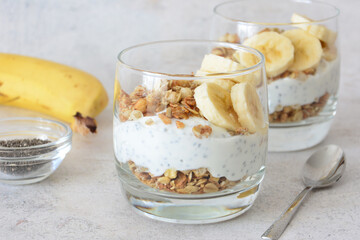 Delicious layered yogurt parfait with banana slices, chia seeds and granola