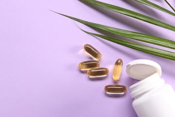 Collagen capsules and leaves on violet background, flat lay. Space for text