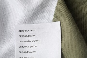 Clothing label with material content on color garment, above view