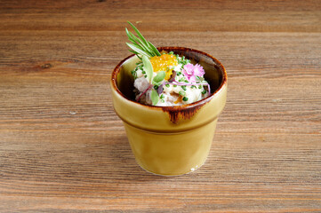 A small bowl of food with a flower on top. The bowl is brown and has a green stem