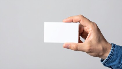 Hand Holding Blank Business Card: A close-up shot of a hand holding a blank white business card against a simple gray background, perfect for showcasing your branding or design.