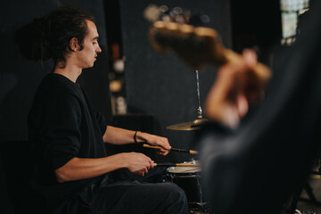 A drummer playing in a music studio, focusing on practice during band rehearsal.
