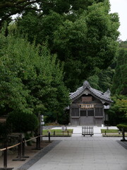 Obraz premium A peaceful Japanese shrine surrounded by lush greenery, traditional wooden architecture, and a serene stone pathway leading up to the entrance. A tranquil and spiritual atmosphere in nature.