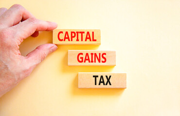 Capital gains tax symbol. Concept words Capital gains tax on beautiful wooden block. Businessman's hand. Beautiful white background. Business and capital gains tax concept. Copy space.