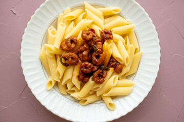 Close-up of penne pasta with shrimps on a plate, Mediterranean style with tomatoes