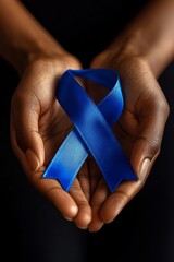 Close-up of hands holding a blue awareness ribbon against a dark background, symbolizing support or remembrance