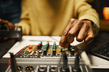Close-up of dj using mixing console for record podcast in studio