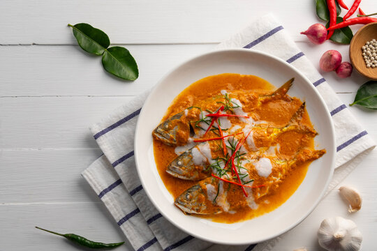 Mackerel fish with red curry sauce topped with shredded kaffir lime leaves and chilli,Thai Chu Chee Fish Curry with coconut milk in white plate.Top view.