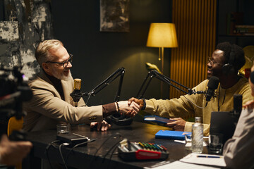Man shaking hands with writer and greeting him during podcast in studio