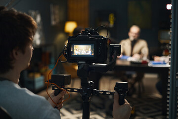 Operator using professional camera to shoot video of podcast in studio