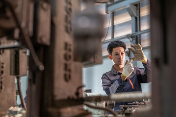 Factory technician focusing on machine calibration in an industrial setting. Precision engineering,...