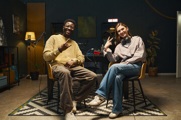 Young people posing at camera and gesturing during interview in office