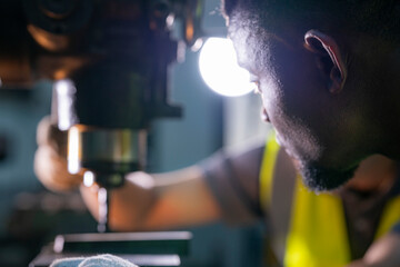 Skilled worker focused on operating machinery in a factory. Wearing high visibility vest and gloves, demonstrating precision, technical ability, safety, and industrial expertise.