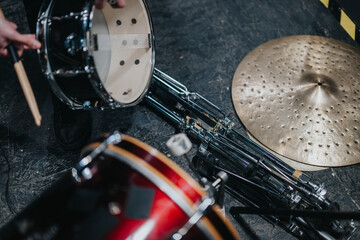 Detailed overhead view of a snare drum, a cymbal, and other drum set parts in a rehearsal or...