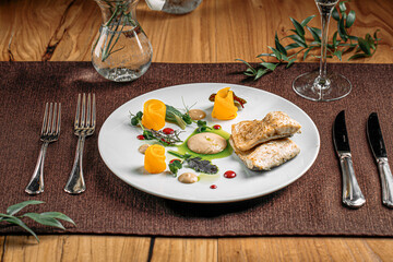 Portion of gourmet white fish dish with fruit slices and sauce