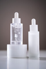 Two serums and a cream in a jar in the rays of the sun.