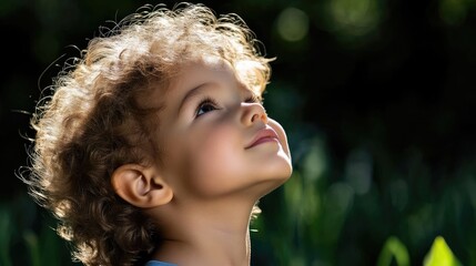 Child looking upward, full of wonder.  A cherubic face, curly hair, and a hopeful gaze
