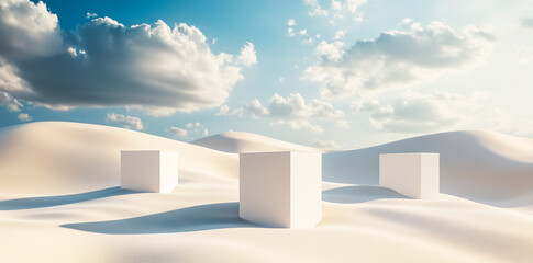 Three white cubes placed on smooth sand dunes under a blue sky with clouds. 
