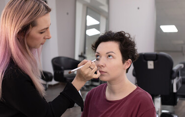 Makeup artist doing professional makeup in visage studio.