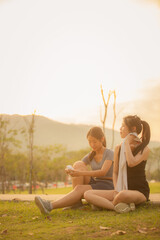 Two young Asian women jogging on a street in a park in the evening under the beautiful golden...