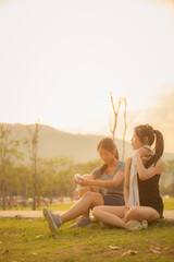 Two young Asian women jogging on a street in a park in the evening under the beautiful golden...
