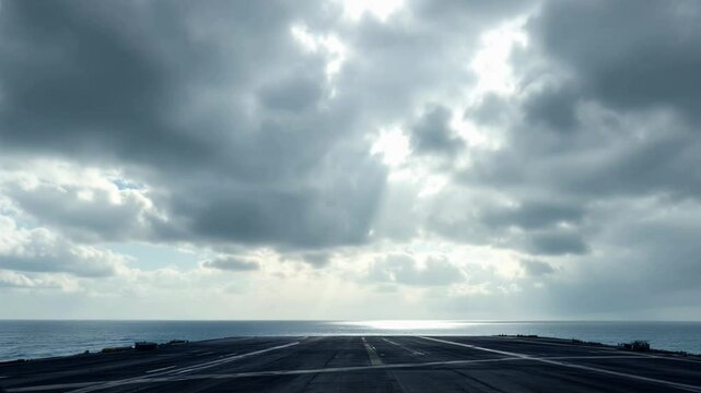 Aircraft carrier deck, stormy sky, and sun breaking through. A dramatic view from the deck of an aircraft carrier, looking out at a stormy sky with patches of sunlight piercing the clouds.