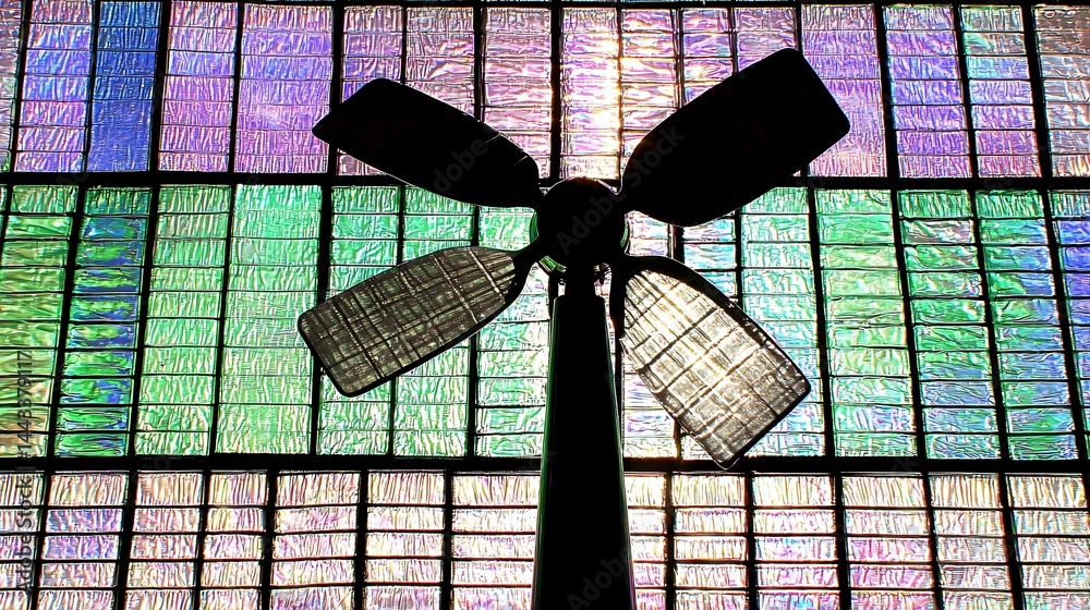 Wall mural wind turbine positioned in front of a stained glass window creating a unique fusion of nature and ar