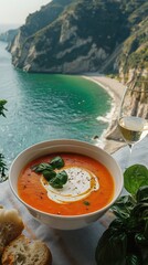 Creamy tomato soup served outdoors with breathtaking coastal view.