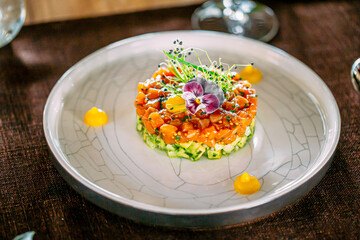 Portion of layered gourmet salad with salmon and cucumber