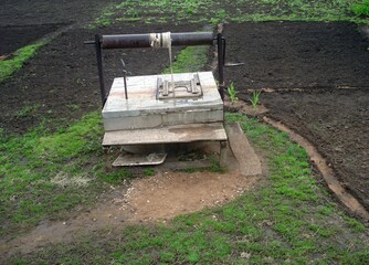 Manual water pump in rural farmland with green vegetation