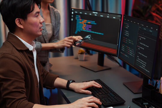 IT developers discussing with point to intelligent website development coder system running data online two screens information technology at neon light room at modern office. Infobahn.