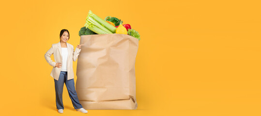 A customer stands beside a large paper bag overflowing with fresh produce, showcasing a vibrant...