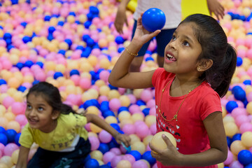Children play with colorful balls in a bouncy ball pit