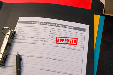 Commercial loan application with approved stamp on desk