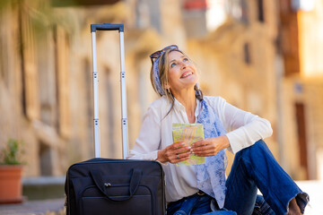adult woman traveling sitting with map and suitcase