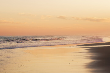 Sunset casts a warm glow over the serene beach scene.