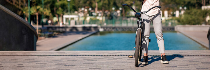 Modern worker, manager, motivation and healthy lifestyle in city. Man in sunglasses wears helmet, stands with bicycle in park near fountain in morning, outdoor