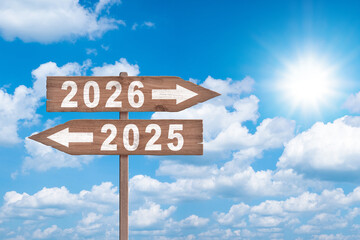 Text 2026 and 2025 written on the wood arrow with sky background. Concept of planning, goal, challenge, new year resolution.