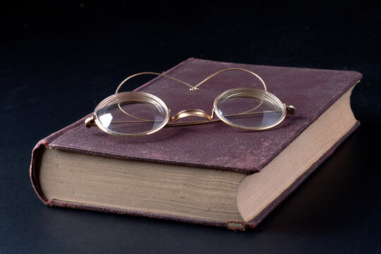 Occhiali da lettura su un vecchio libro su sfondo nero